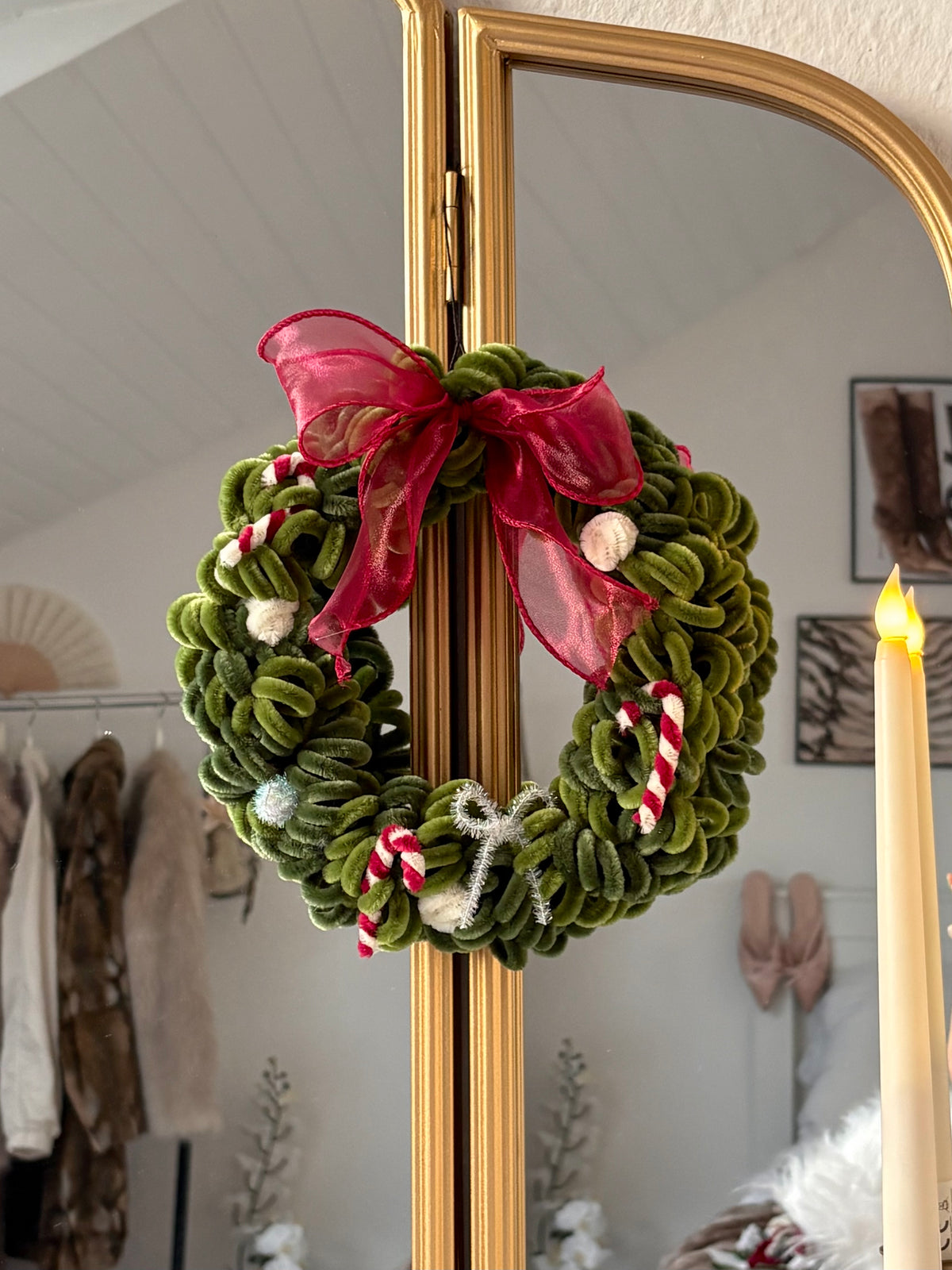Handmade Christmas wreath made from green pipe cleaners with a red bow and festive decorations